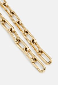 Catena in metallo dorato con anelli ovali dalla finitura lucida. Tra i dettagli notevoli c'è il marchio inciso su un anello. Progettata per essere durevole.