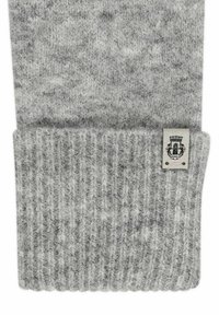 Grau gestrickter Schal mit gerippter Textur und umgeschlagenem Saum. Ein kleines Etikett ist sichtbar, das ein Wappen-Design und erklärenden Text zeigt.