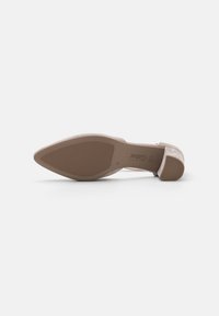 Scarpa con tacco alto beige, con punta affusolata e suola testurizzata. Presenta una tomaia in morbida suede e un tacco snodato e sottile.