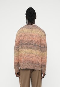 Πλεκτό πουλόβερ με διαβαθμισμένο σχέδιο σε αποχρώσεις του πορτοκαλί, κίτρινου και καφέ, με άνετη εφαρμογή και στρογγυλή λαιμόκοψη, από υφασμάτινη υφή.