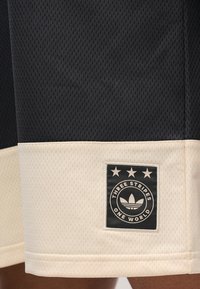 Μαύρο αθλητικό σορτς με υφασμάτινη πλέξη και υφή διχτυού, με κρεμ χρώματος τελείωμα και υφασμένη ετικέτα με τρία αστέρια και έμβλημα.