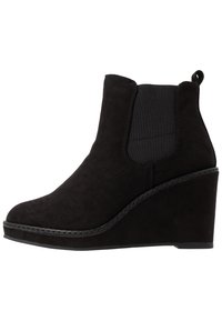 Botte de cheville noire à talon compensé en daim avec une finition lisse, dotée de panneaux élastiques sur les côtés et d'une languette à l'arrière.