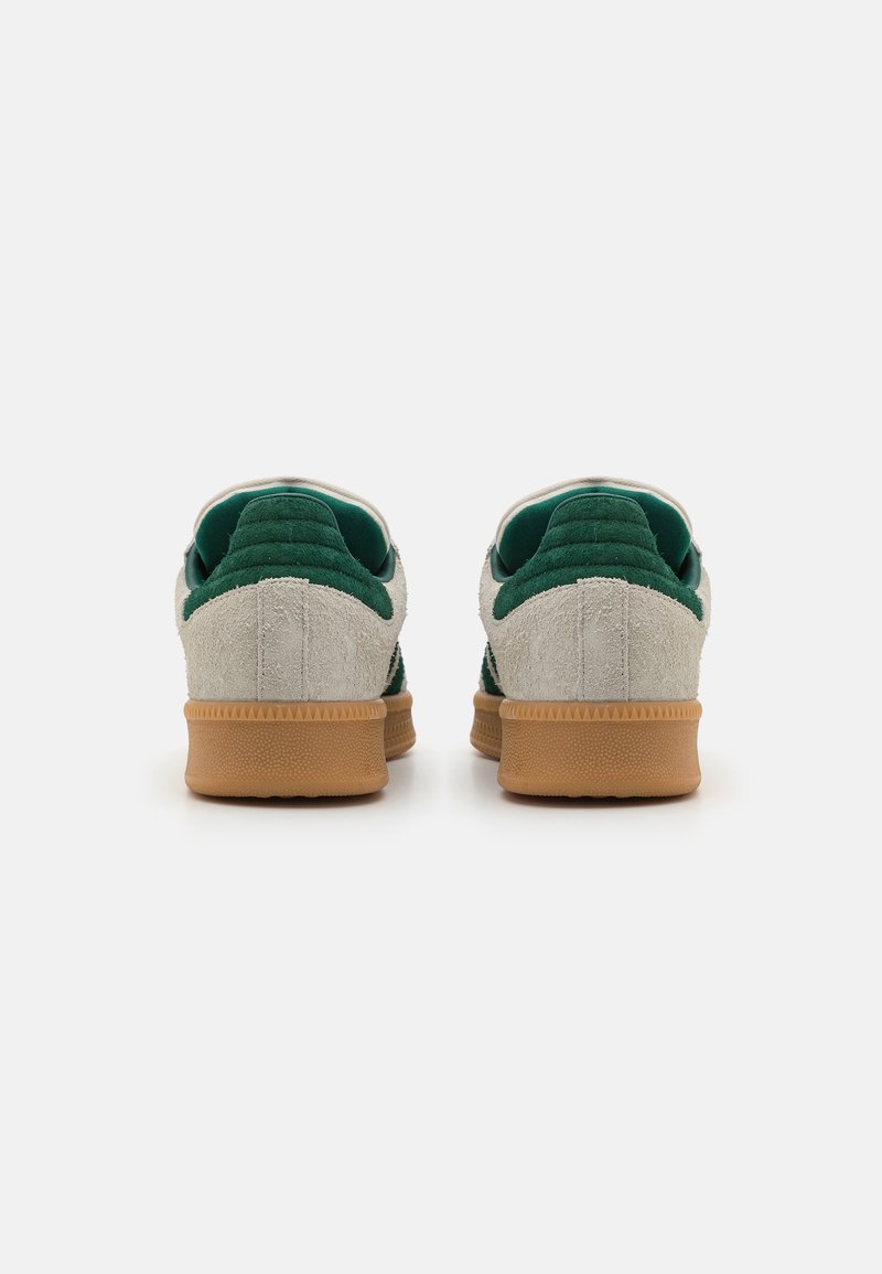 Zapatillas de ante verdes y beige con suela de goma, que cuentan con un cuello acolchado y acentos texturizados en el talón. Vista trasera.