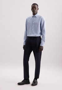 Camicia a quadri blu chiaro con maniche lunghe, colletto abbottonato, abbinata a pantaloni navy scuri e scarpe nere stringate.