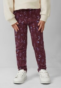 Bordowe legginsy z kwiecistym wzorem w niebieskie i białe kwiaty, charakteryzujące się dopasowanym krojem, elastycznym pasem i zestawione z białymi sneakersami.