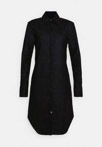 Svart randig skjortklänning med spetsig krage, långa ärmar och rundad nederkant. Har en framslutning med knappar och en slät textur.