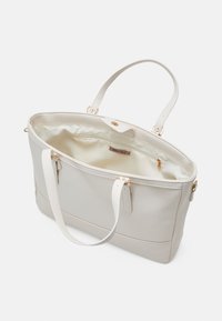 Sac fourre-tout gris clair en matériau synthétique lisse, doté de deux bandoulières, d'une poche intérieure zippée et de subtils accents en métal doré.