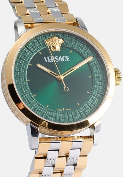 Orologio da polso in metallo dorato e argento con quadrante verde texture, caratterizzato da un logo a testa di leone, indicatori delle ore dorati e un bracciale a motivo.