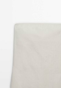 Gros plan d'un tissu beige avec une texture tissée subtile, présentant un bord droit sur fond blanc.