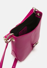 Roze leren schoudertas met een gepolijste afwerking, externe hardwareringen en een contrasterende zwarte binnenkant met een ritsvak.