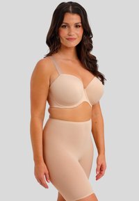 Bežová vyztužená podprsenka s nastavitelnými ramínky, hladký povrch, podprsenka s kosticemi. V kombinaci s odpovídajícími vysokými tvarujícími šortkami.