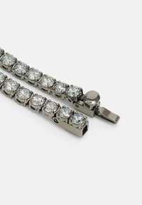 Narukvica pozlaćena rodijem s prozirnim rhinestones u povezanoj konstrukciji, s kutijom za zatvaranje i glatkom metalnom površinom.