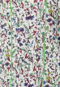Blusa di tessuto bianco con vivace stampa floreale in viola, rosso e verde. Presenta bottoni e cuciture di colore verde lungo le cuciture.
