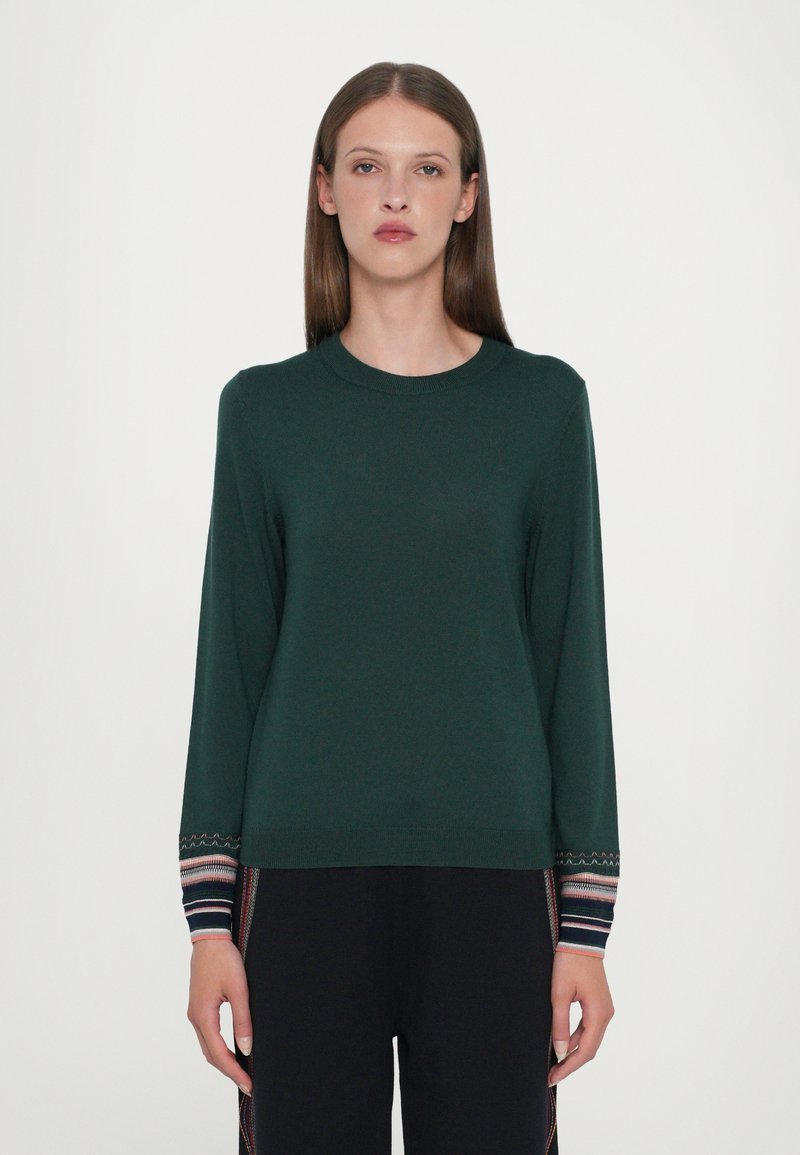 Pulover verde din tricot, cu guler rotund, mâneci lungi și manșete cu model, având dungi orizontale în diverse culori.
