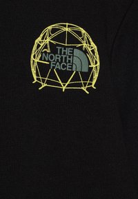 Čierna textília s žltým geometrickým logom a nápisom "THE NORTH FACE" v zelenej farbe v rámci dizajnu. Hladký povrch, jednoduché a čisté.