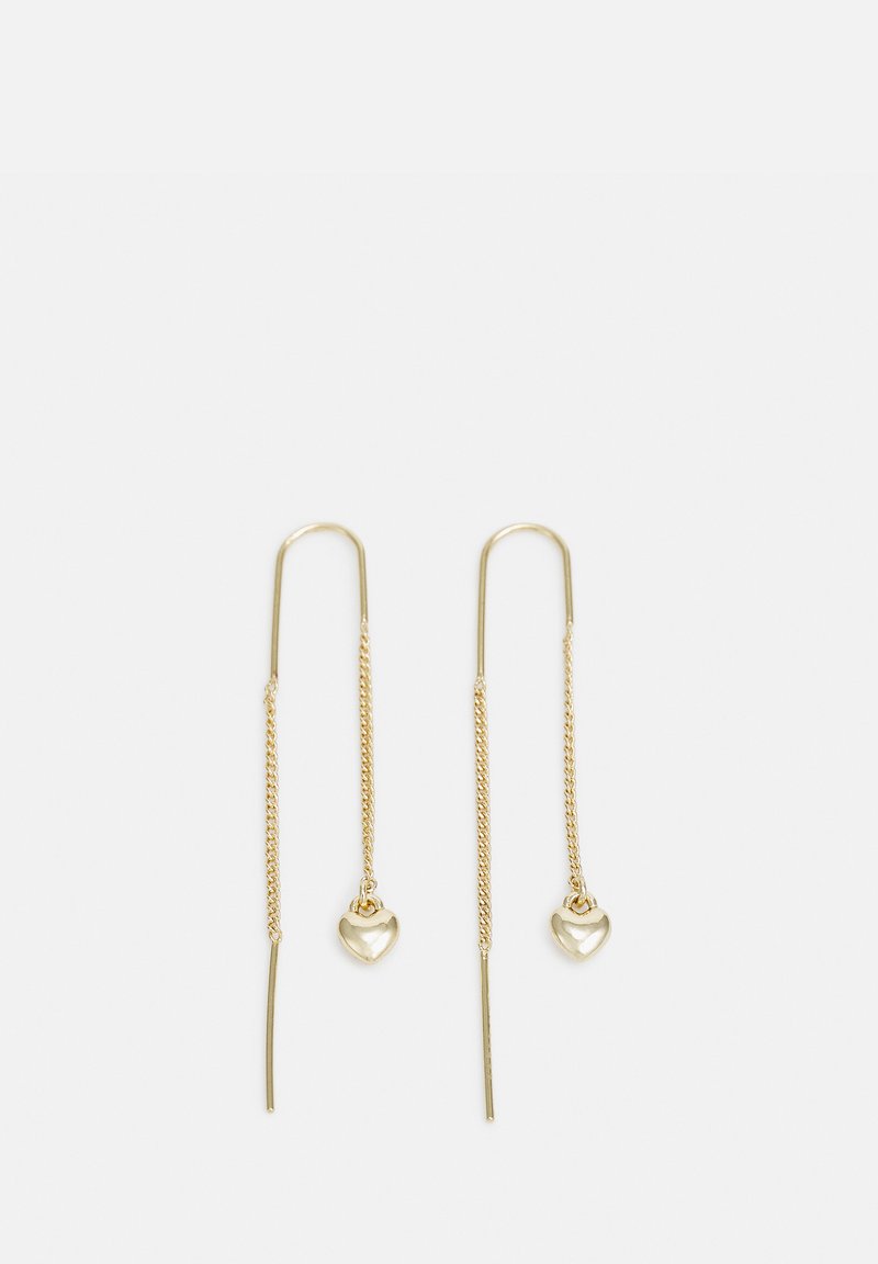Des boucles d'oreilles en chaîne couleur or présentent des designs de bâton allongés avec de petits pendentifs en forme de cœur à l'extrémité. Texture lisse, style minimaliste.