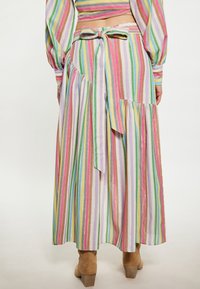Abito a righe multicolore con maniche lunghe, vita cintata e dettaglio con fiocco sul retro. Realizzato in tessuto leggero con orlo arricciato.