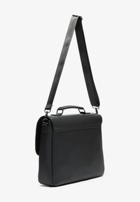 Sac messenger en cuir noir avec une forme structurée, doté d'une poignée supérieure, d'une sangle réglable et d'un design minimaliste. Texture lisse.
