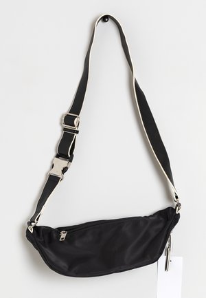 Zwarte crossbodytas van nylon met een gebogen vorm, een ritsvak, verstelbare riem en zilverkleurige hardware accenten. Glad oppervlak, minimalistisch ontwerp.