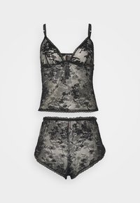 Čierna čipkovaná súprava spodnej bielizne, ktorá obsahuje crop top s vlnitým lemom a nastaviteľnými ramienkami, spárovaný s rovnakými vysokými šortkami.