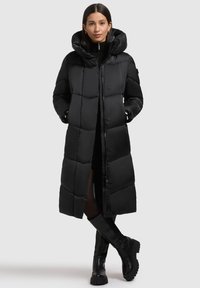 Schwarzer Steppmantel mit gesteppter Optik, hohem Kragen und Reißverschluss vorne. Der kniehohe Mantel verfügt über eine Kapuze und Seitentaschen.