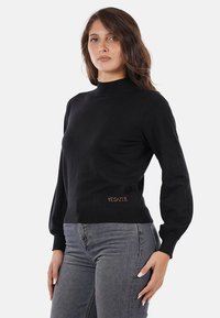 Maglione nero a maglia con collo alto e maniche lunghe, caratterizzato da un motivo testurizzato e logo "YESZEE" in colore contrastante sull'orlo.