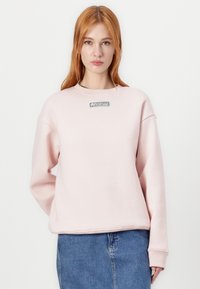 Felpa rosa chiaro realizzata in misto cotone, con colletto rotondo, spalle dropout, polsini a coste e logo Lacoste nero sul davanti.