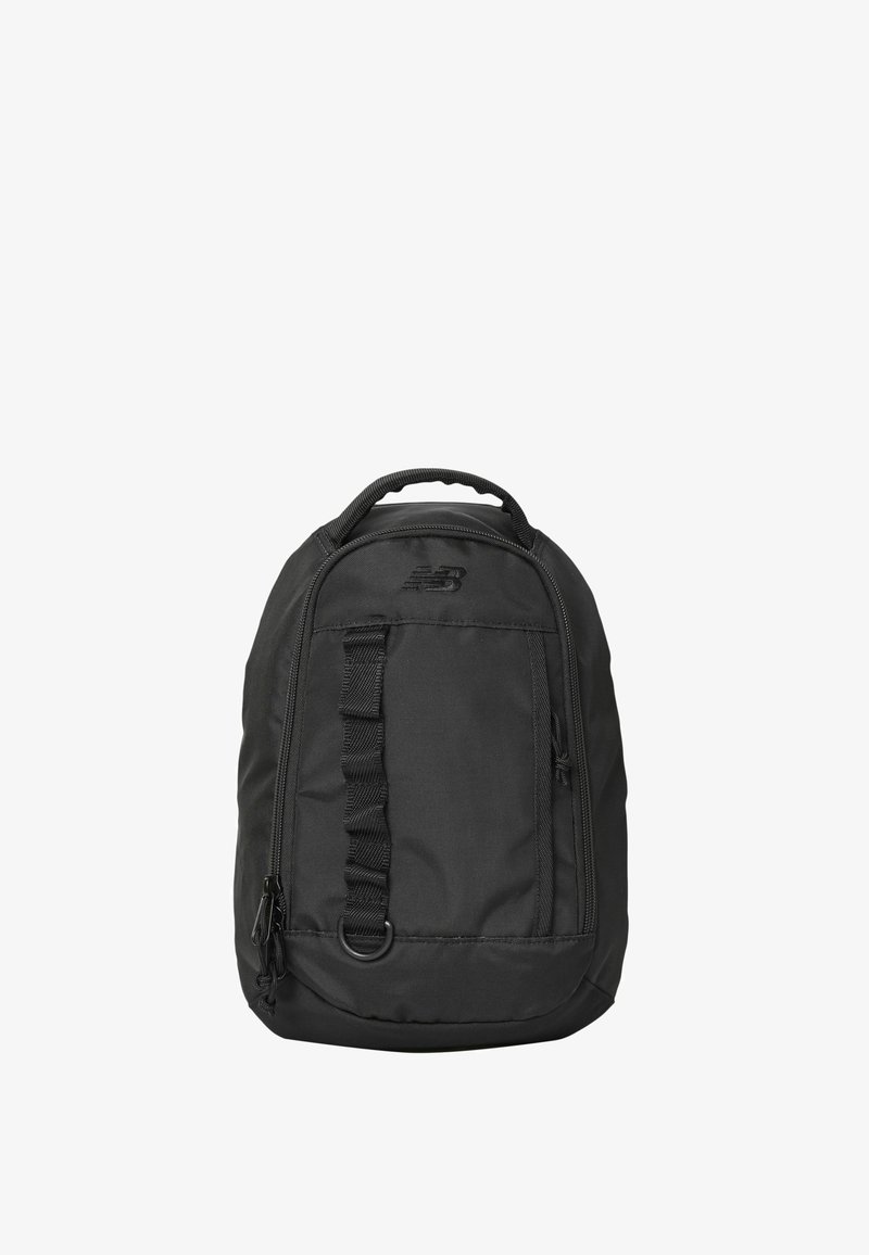 Sac à dos compact noir avec poignée supérieure, poche avant zippée, boucles de sangle et logo New Balance sur le panneau avant supérieur.