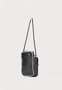 Borsa in pelle nera con piping bianco, forma rettangolare, tracolla regolabile, tasca frontale con zip, texture liscia e design minimalista.