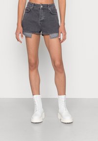 Pantalones cortos de mezclilla gris de cintura alta con dobladillos enrollados y bolsillos frontales, combinados con botas de tobillo blancas con cordones. Textura suave, diseño informal.