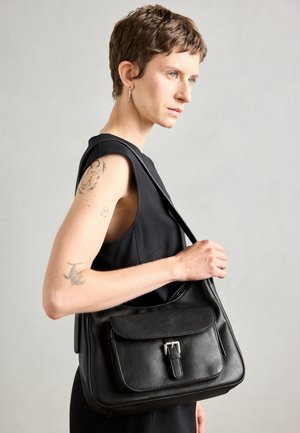 Melnas ādas pleca soma ar priekšējo atloku, sprādzes detaļu un gludu tekstūru. Iespējota viena pleca siksna un minimālisma dizains.