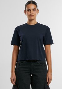 Tamsiai mėlynas, trumpas T-shirts, pagamintas iš švelnios medvilnės, su klasika stiliaus apvalia iškirpte ir trumpomis rankovėmis; pasižymi paprastu ir švariu dizainu.