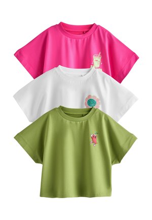 Three cropped t-shirts in pink, white, and green, each with a small colorful cartoon graphic on the upper left chest.