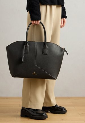 Sac fourre-tout en similicuir noir avec un design structuré, poignées supérieures et un logo doré à l'avant. Fermeture zippée et surface texturée.