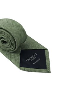Cravate en chevrons vert fabriquée en tissu texturé, soigneusement enroulée. Comprend une étiquette bleu foncé avec "HACKETT LONDON" et "FABRIQUÉ EN ITALIE" imprimé.