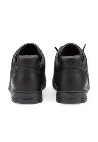 Par de zapatillas de cuero negro vistas desde atrás, con cuellos acolchados, logotipo de palos de hockey cruzados en relieve y la marca "LLOYD" en los talones.