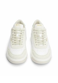 Weiße Sneaker aus glattem Leder und Wildleder, mit perforierten Details, flachen beigen Schnürsenkeln und einem hellgrünen Akzent an der Ferse.