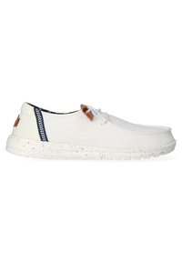 Des chaussures en toile de couleur blanc cassé avec une surface texturée et une semelle en caoutchouc mouchetée. Présentent des accents en cuir marron et des détails rayés bleu marine.