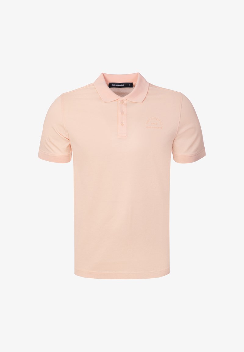 Polo rose clair à manches courtes avec col et trois boutons, avec un texte brodé discret sur la poitrine gauche.