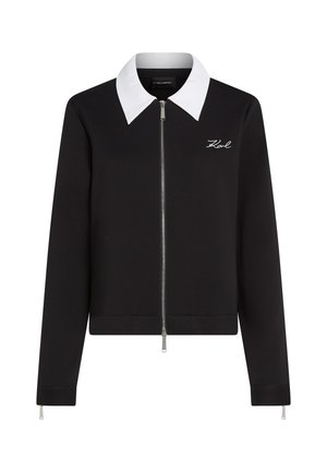 Juodas užtraukiamas džemperis su kontrastinga balta apykakle, turintis liesą siluetą ir išsiuvinėtą logotipą kairėje krūtinės pusėje. Lygi tekstūra.