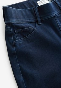 Dunkelblaue, hoch sitzende, weit geschnittene Jeans aus Denim, mit einer Fronttasche, sichtbaren Nähten und einem Etikett, das in den Bund eingenäht ist.