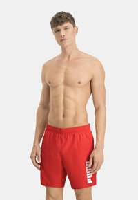 Bañador rojo con cinturilla elástica y estampado del logotipo "PUMA" en blanco en el lado izquierdo, fabricado con un material suave y ligero.