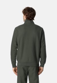 Felpa verde scuro, con texture, colletto alto, maniche lunghe e polsini a costine. La vista posteriore mostra una vestibilità comoda e un design senza cuciture.