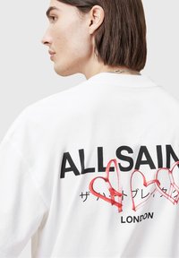 White cotton sweatshirt featuring a large graphic print with "ALLSAINTS" in bold black text and red heart outlines on the back.