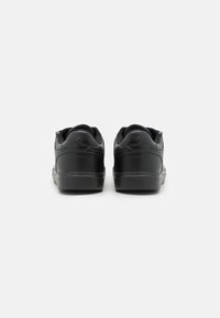 Schwarze Sneakers mit einem Obermaterial aus glattem Leder, runder Zehenpartie, gepolstertem Schaft und profiliertem Gummisohlen. Mit Nähten und Logodetails an der Ferse.