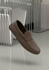 Brune læder loafers med en struktureret overflade, syede detaljer og rund tå. Letvægts, fleksibel sål med minimale designakcenter.