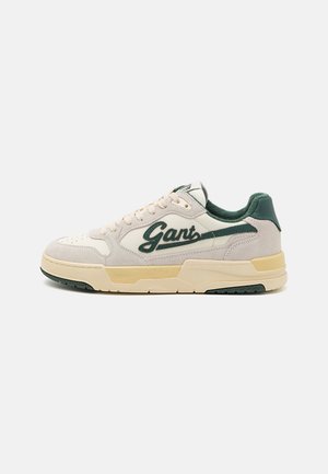 Sneakers with a cream suede and leather upper, green accents, perforated toe, and beige rubber sole. Features "Gant" logo on the side.