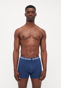 Navy blue boxer shorts made of soft cotton, featuring a thick white elastic waistband with "BJÖRN BORG" branding and a snug fit.