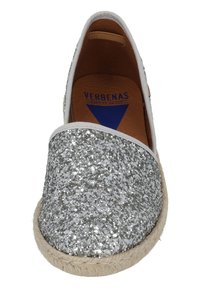 Scarpa slip-on scintillante argento con tomaia in tessuto, suola in juta naturale e bordo bianco. L'interno presenta una soletta in pelle marrone con logo.