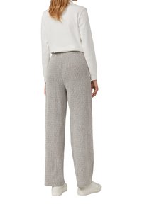 Hellgraue weite Hosen aus strukturierter Strickware mit einem elastischen Bund. Getragen mit einem weißen Langarmshirt und weißen Turnschuhen.